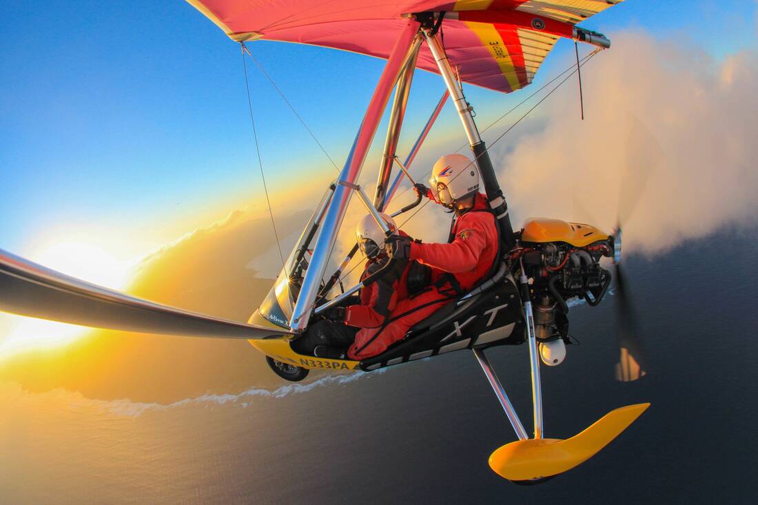Hands on the control bar, flying toward a low sun through clouds